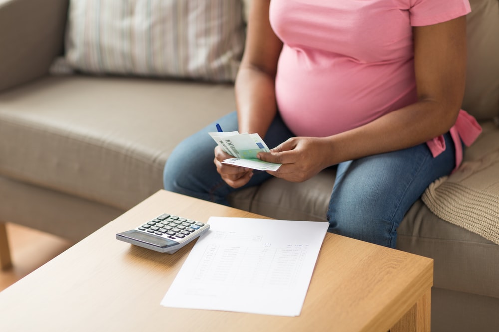 webbabyshower mom-to-be budgeting with money calculator and paper on table