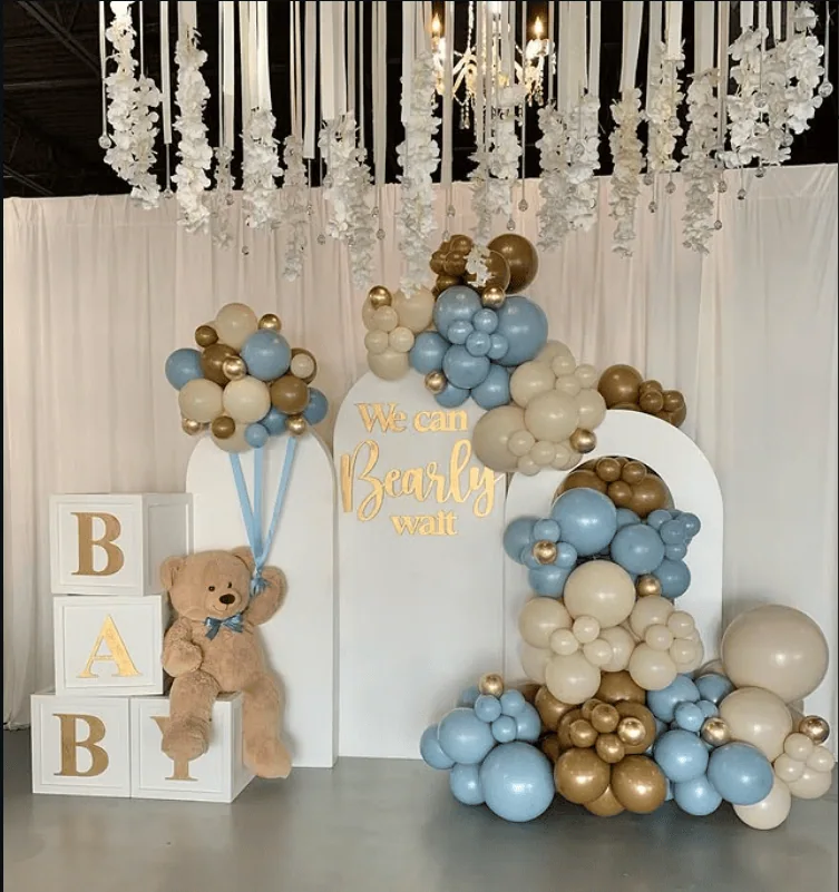 Baby shower balloon arrangement with teddy bear, "We can Bearly wait" sign, and decorative blocks.
