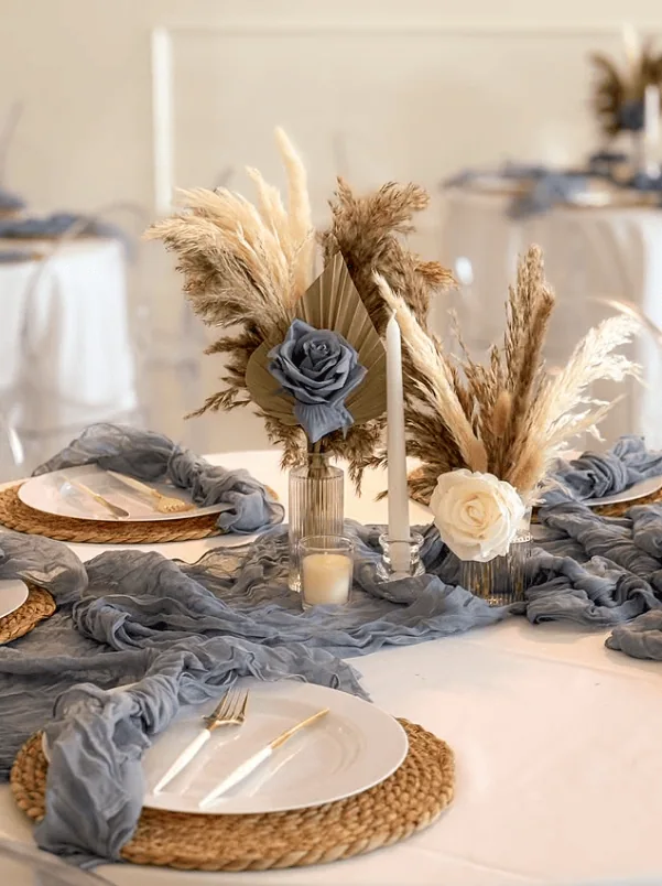 Elegant boho-themed baby shower table with pampas grass and floral arrangements.