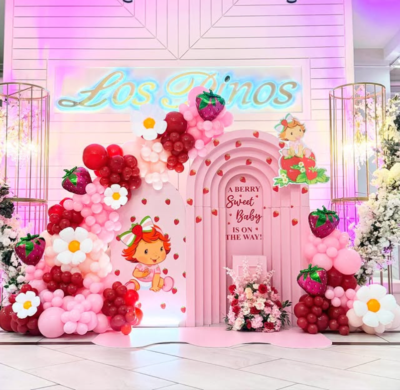 Beautiful pink strawberry-themed balloon arch for a baby shower celebration.