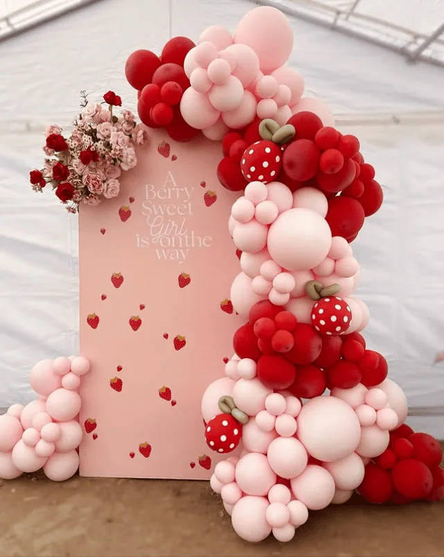 Colorful balloon arch with strawberries for a baby shower celebration.