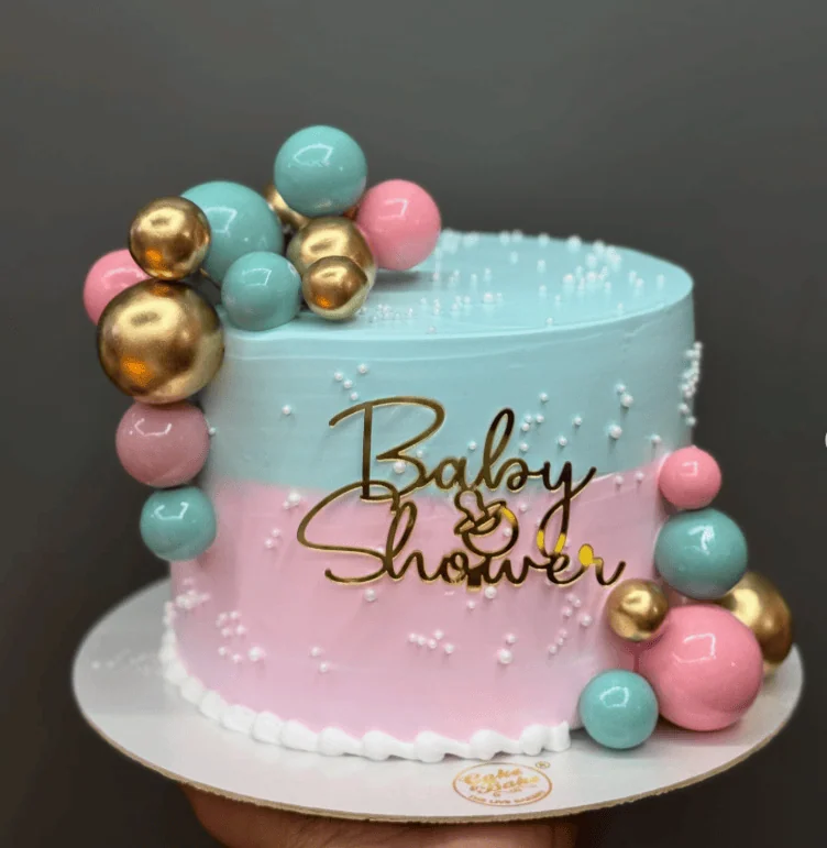 Elegant baby shower cake with pink, blue, and gold accents for a budget-friendly celebration.