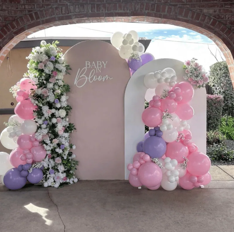 Elegant balloon arch with pink, purple, and white balloons and floral arrangements for a spring baby.
