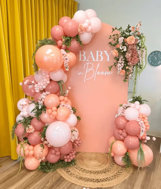 Elegant pink balloon arch with floral accents for spring baby shower.