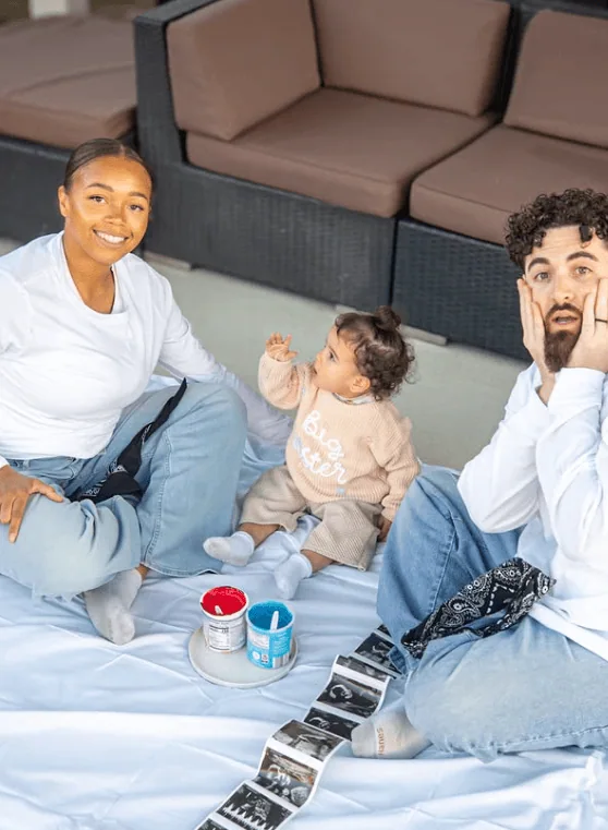 Happy family celebrating a gender reveal with ultrasound pictures and baby items.