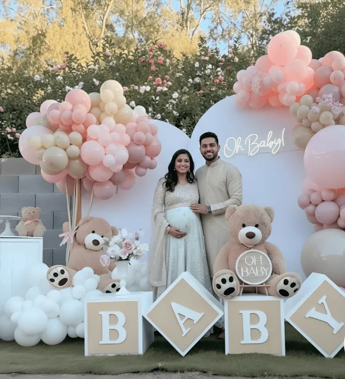 Beautiful couple at gender reveal with balloons and teddy bears.