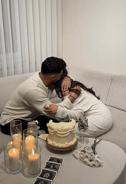 Couple sharing a tender moment during a gender reveal celebration at home.