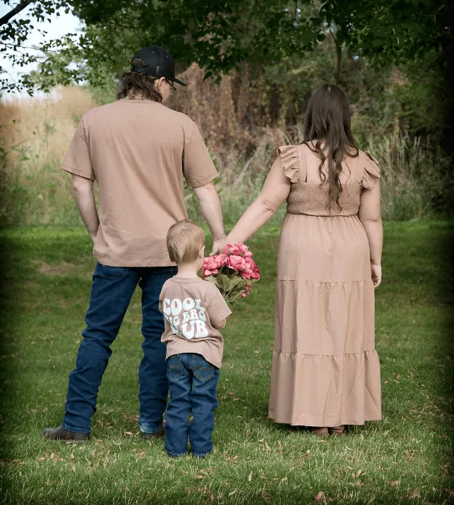 Family holding hands during a gender reveal celebration outdoors.