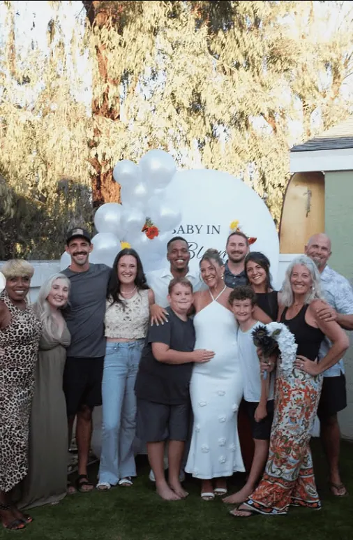 Group of family and friends at a gender reveal celebration with a pregnant woman and festive decorat.