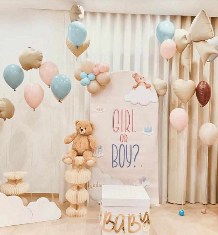 Colorful balloons and teddy bear for gender reveal celebration.