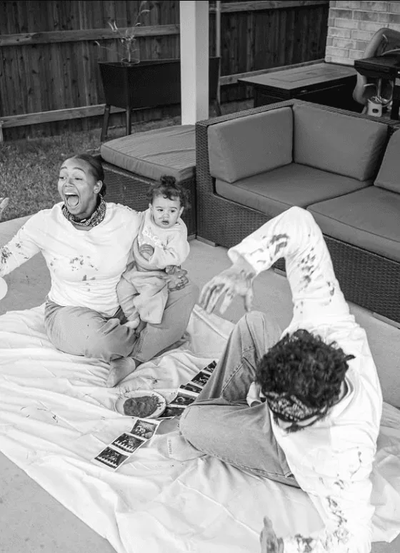 Happy family enjoying a playful moment outdoors with a woman, child, and man during a gender reveal.