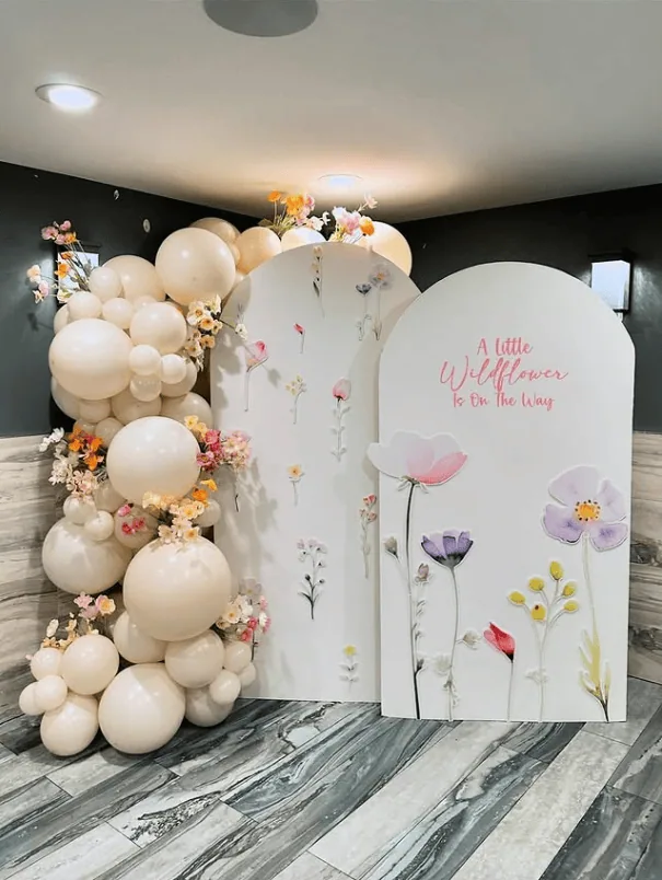 Elegant baby shower backdrop with flowers and balloon arrangement.