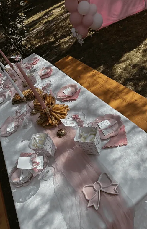 Elegant baby shower table setup with pink and white decorations and treats.