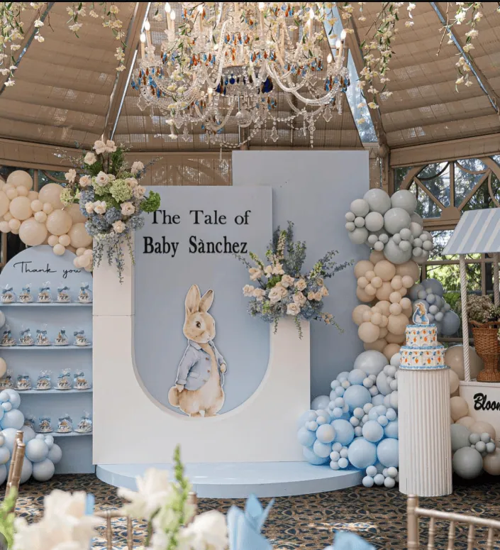 Elegant vintage baby shower setup with floral arrangements, balloons, and a bunny illustration backd.