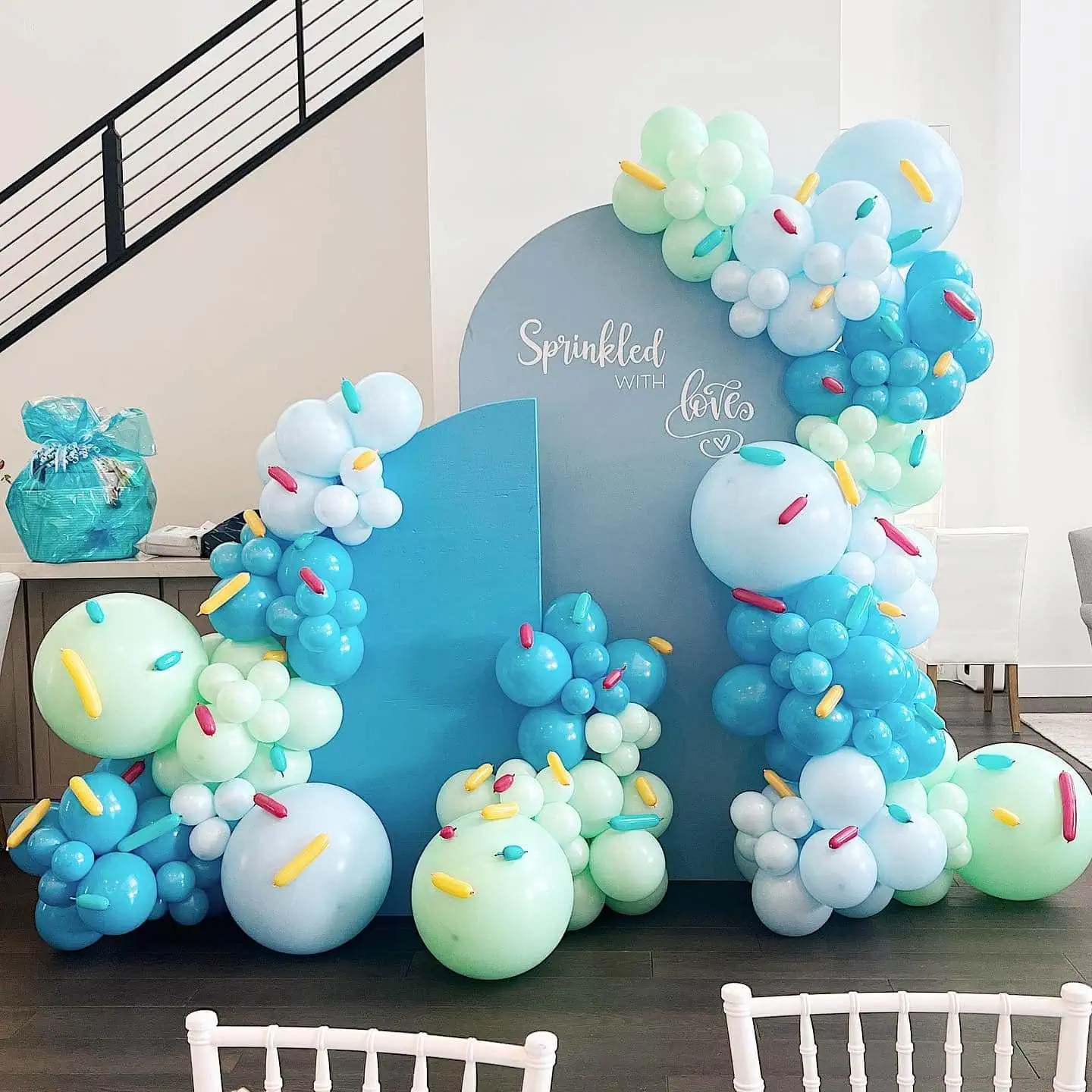 Balloon arrangement with blue, white, and green balloons for a baby shower celebration.