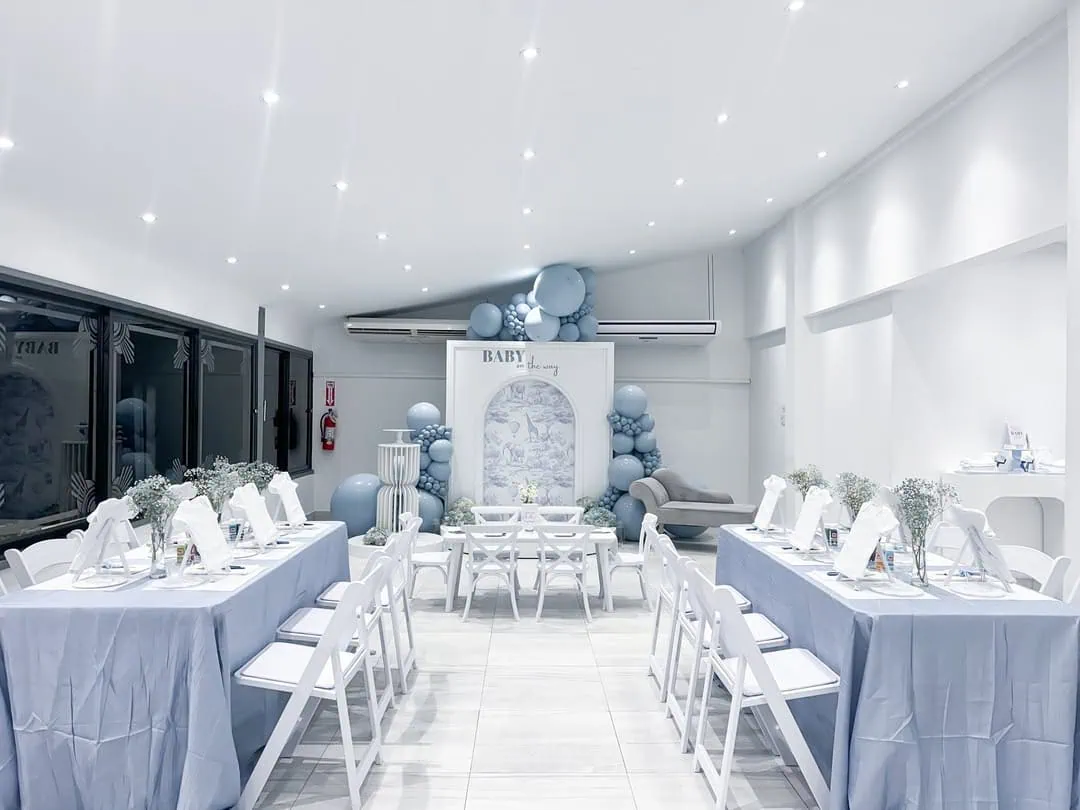 Stylish baby shower table arrangement with blue and white decorations.