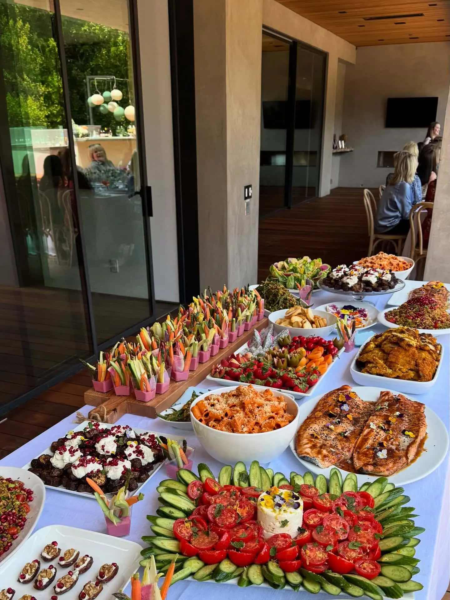 Decorative baby shower food table with cakes, fruits, and snacks in a modern room.