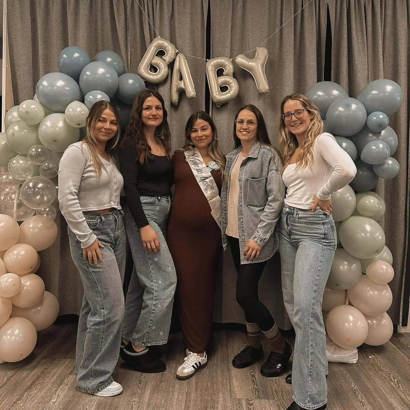 Group of women celebrating a baby shower with balloons and decorations.