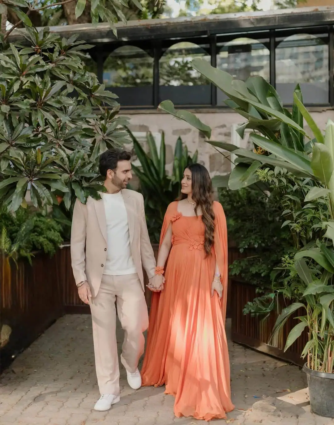 Happy couple holding hands in lush garden setting for baby shower event.