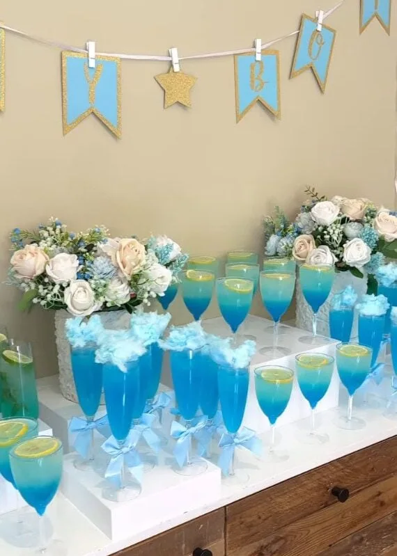 Colorful baby shower drink table with floral arrangements and banners.