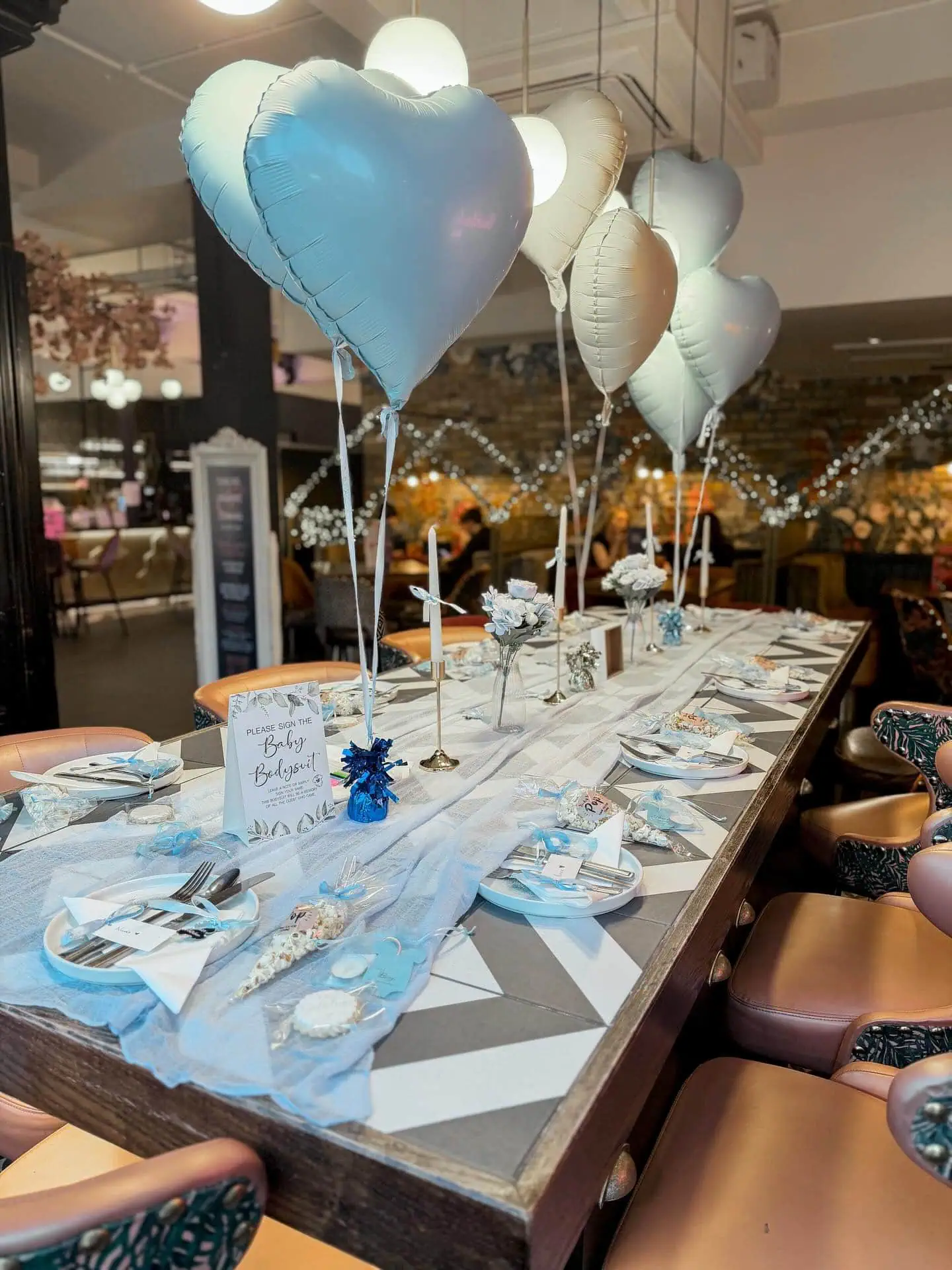 Decorated baby shower table with heart-shaped balloons and elegant table settings.